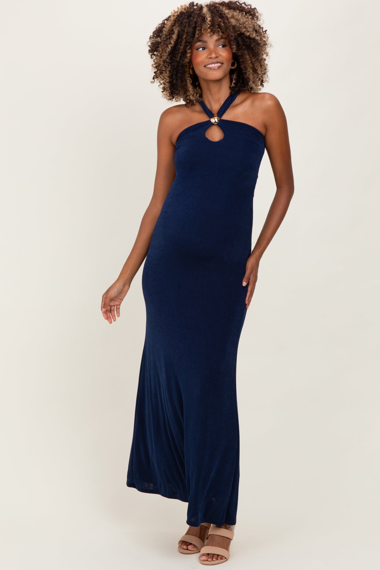 woman wearing a navy blue halter neck maternity dress with a keyhole detail and a flowy skirt, showcasing her baby bump