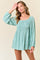 woman wearing a mint green smocked mini dress with long puff sleeves and floral pattern