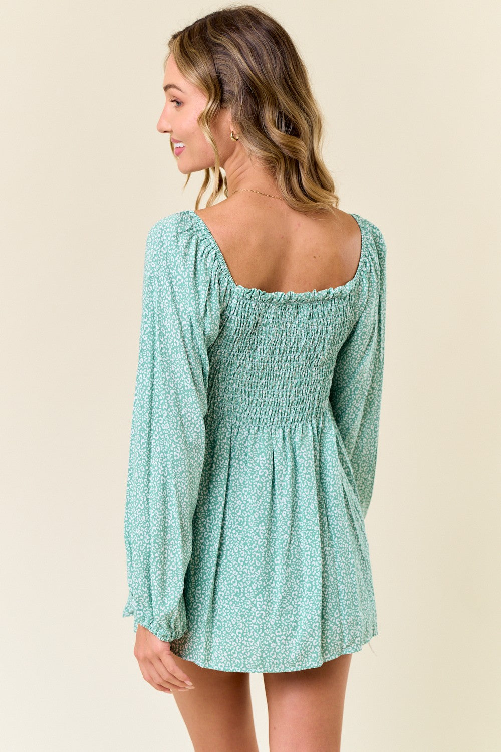 woman wearing a green floral long sleeve mini dress with a smocked back and puff sleeves