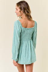 woman wearing a green floral long sleeve mini dress with a smocked back and puff sleeves
