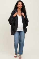 woman wearing a black oversized maternity hoodie, white v-neck top, and blue jeans, showing off her baby bump