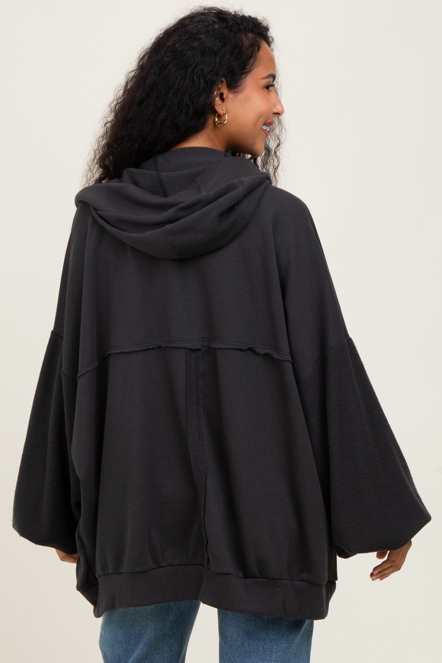 woman wearing a dark gray maternity hoodie with a relaxed fit and wide sleeves, showing off her baby bump from behind