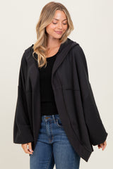 woman wearing a black oversized hoodie with a hood and wide sleeves, paired with blue jeans