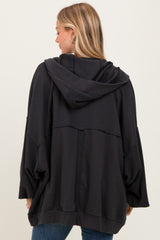 woman wearing a black oversized hoodie with a hood and batwing sleeves, viewed from the back
