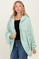woman wearing a mint green oversized hooded cardigan over a black top and blue jeans