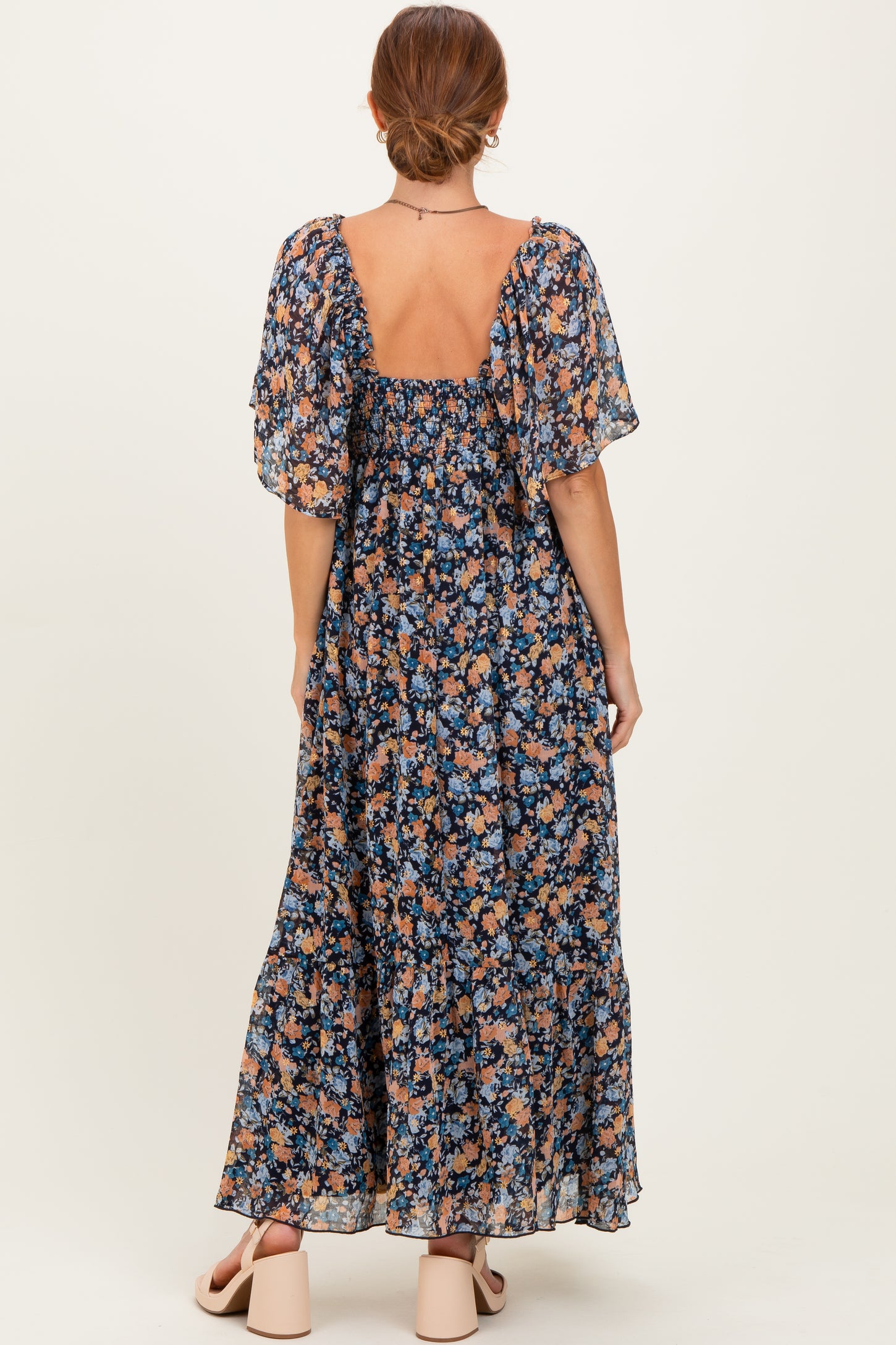 woman wearing a long floral maxi dress with puff sleeves and a square back, shown from the back