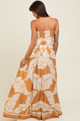 woman wearing a long mustard yellow maxi dress with white leaf print and a smocked back