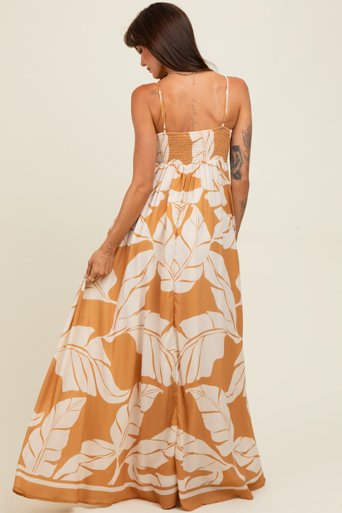 woman wearing a long mustard yellow maxi dress with white leaf print and a smocked back