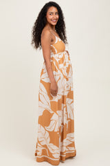 woman wearing a maternity maxi dress with a yellow and white leaf print, showing her baby bump
