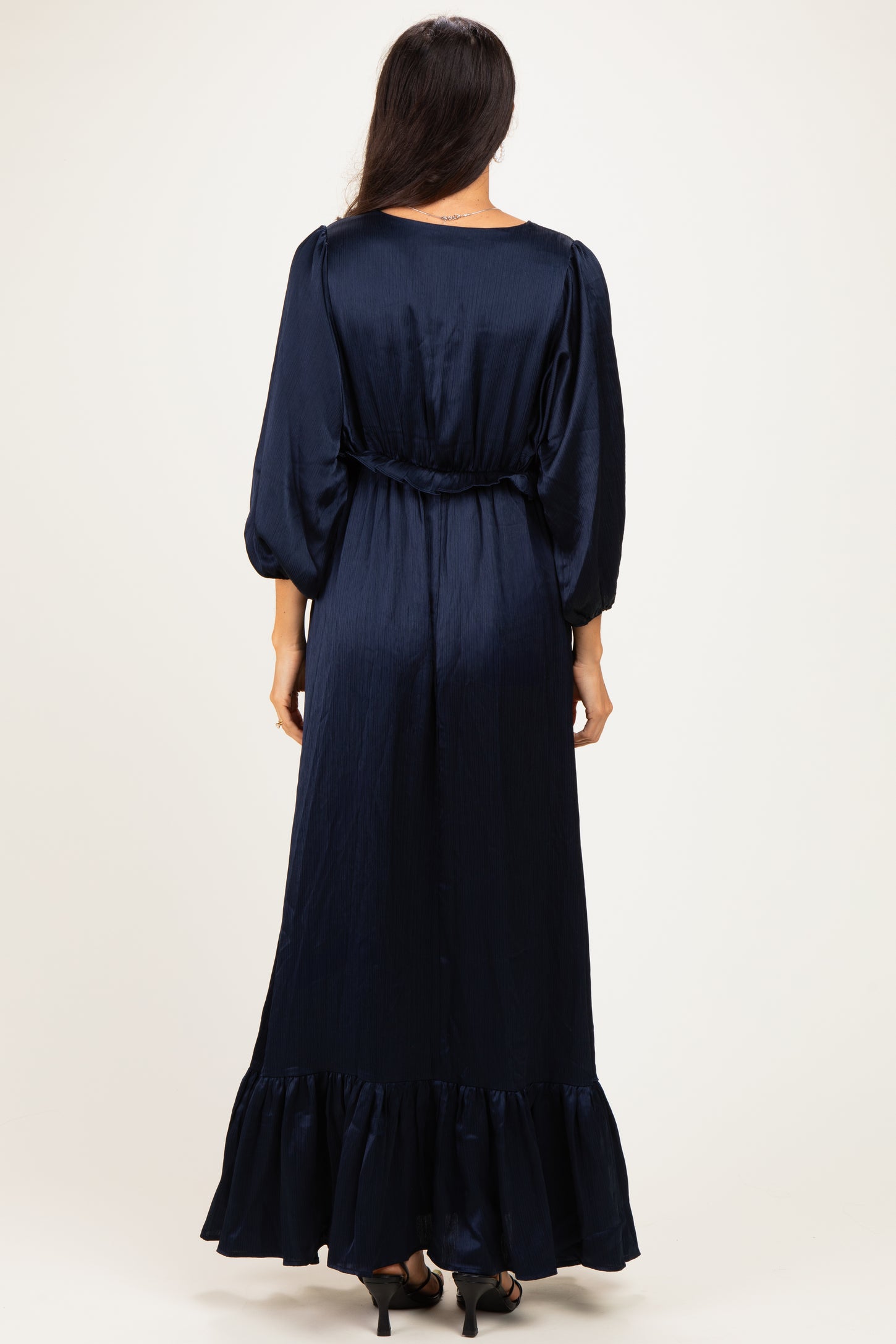 woman wearing a navy blue maxi dress with balloon sleeves and a ruffled hem, shown from the back
