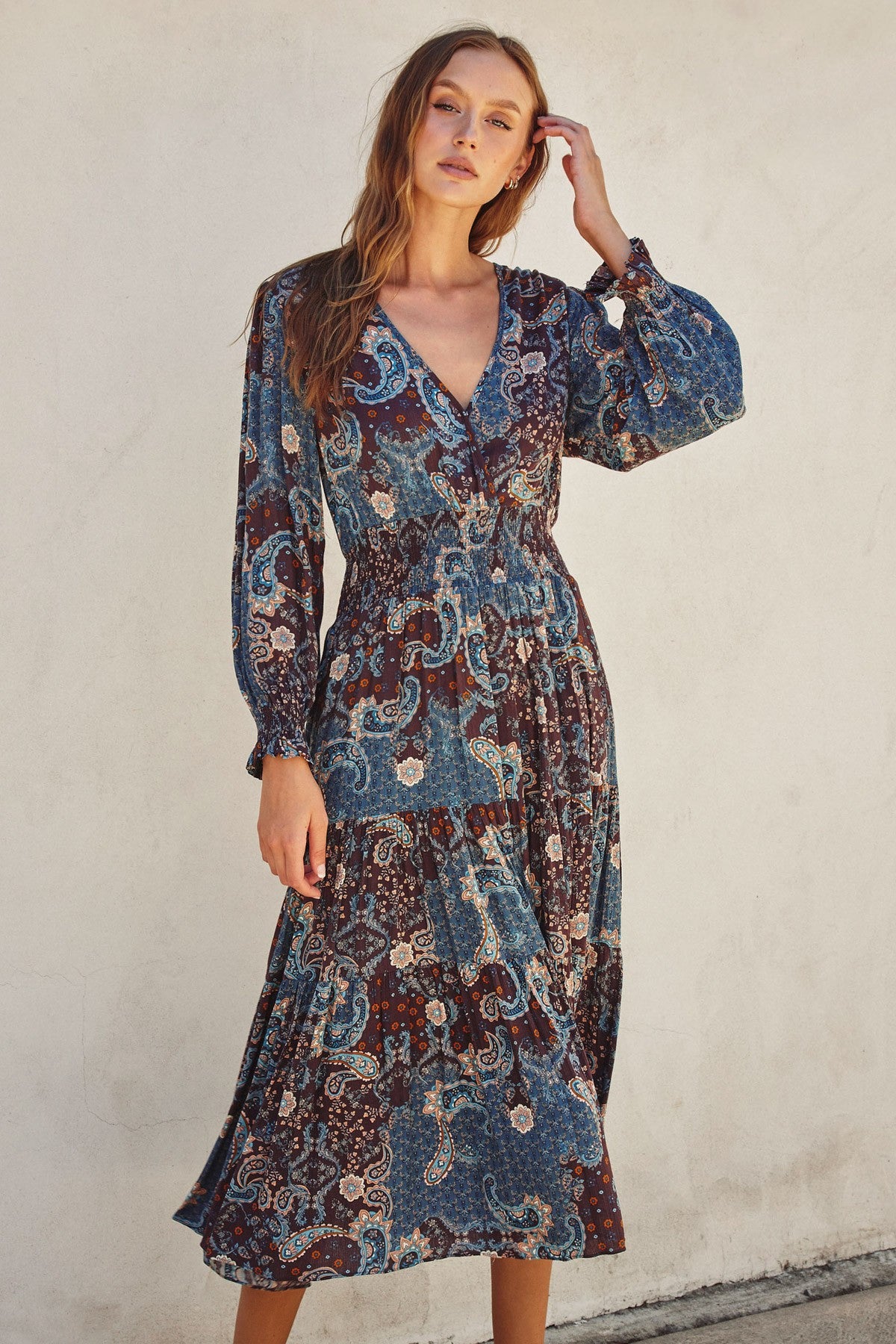 woman wearing a blue floral midi dress with long sleeves and a cinched waist