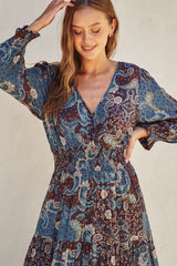 woman wearing a long sleeve paisley print dress with a smocked waist and deep v-neckline