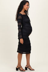 woman wearing a black lace maternity dress with long sleeves, showing her baby bump in a side view