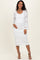 woman wearing a white lace maternity dress with long sleeves and a scoop neckline, gently cradling her baby bump