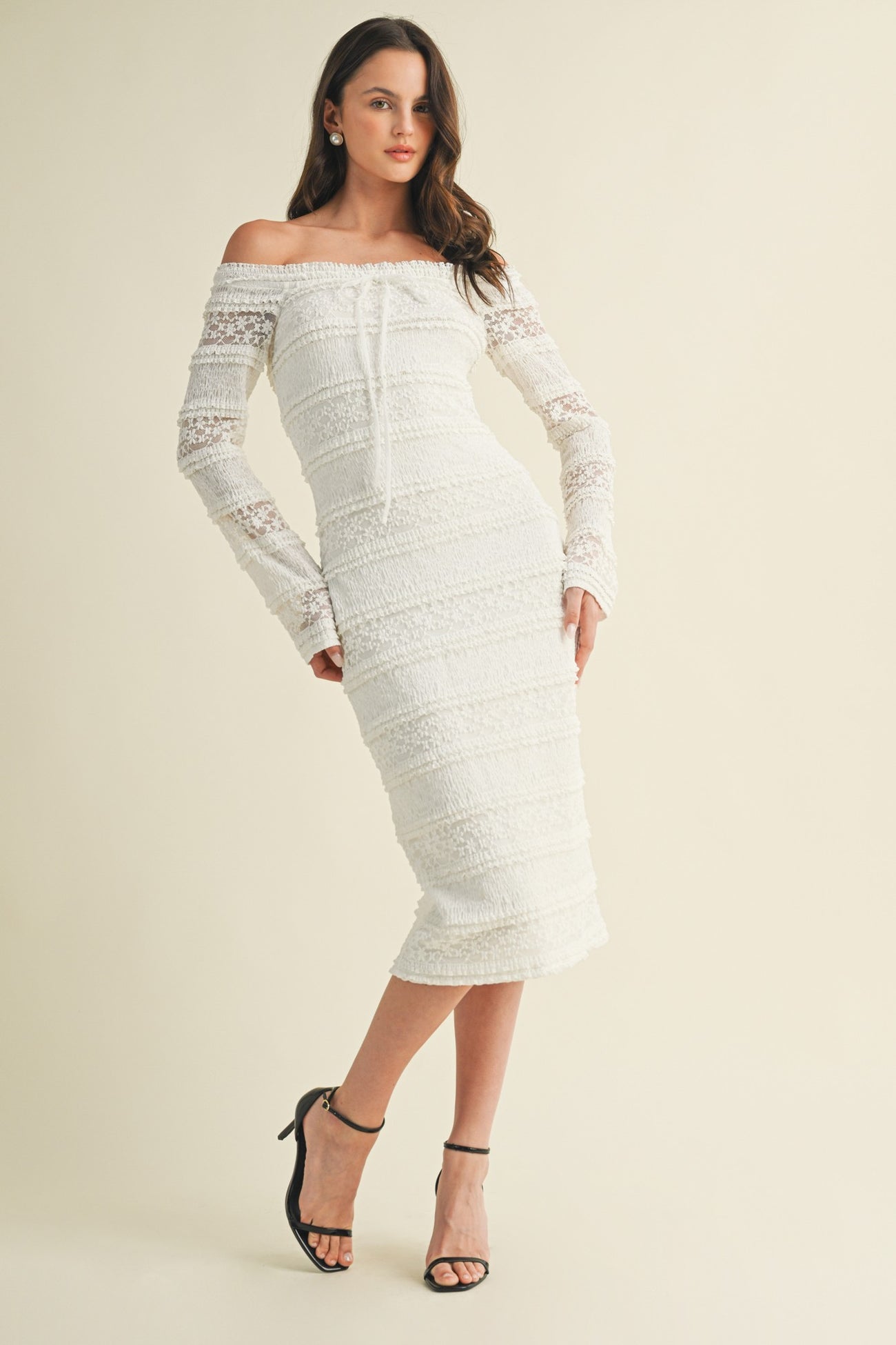 woman wearing a white off-the-shoulder midi dress with lace long sleeves and a fitted silhouette