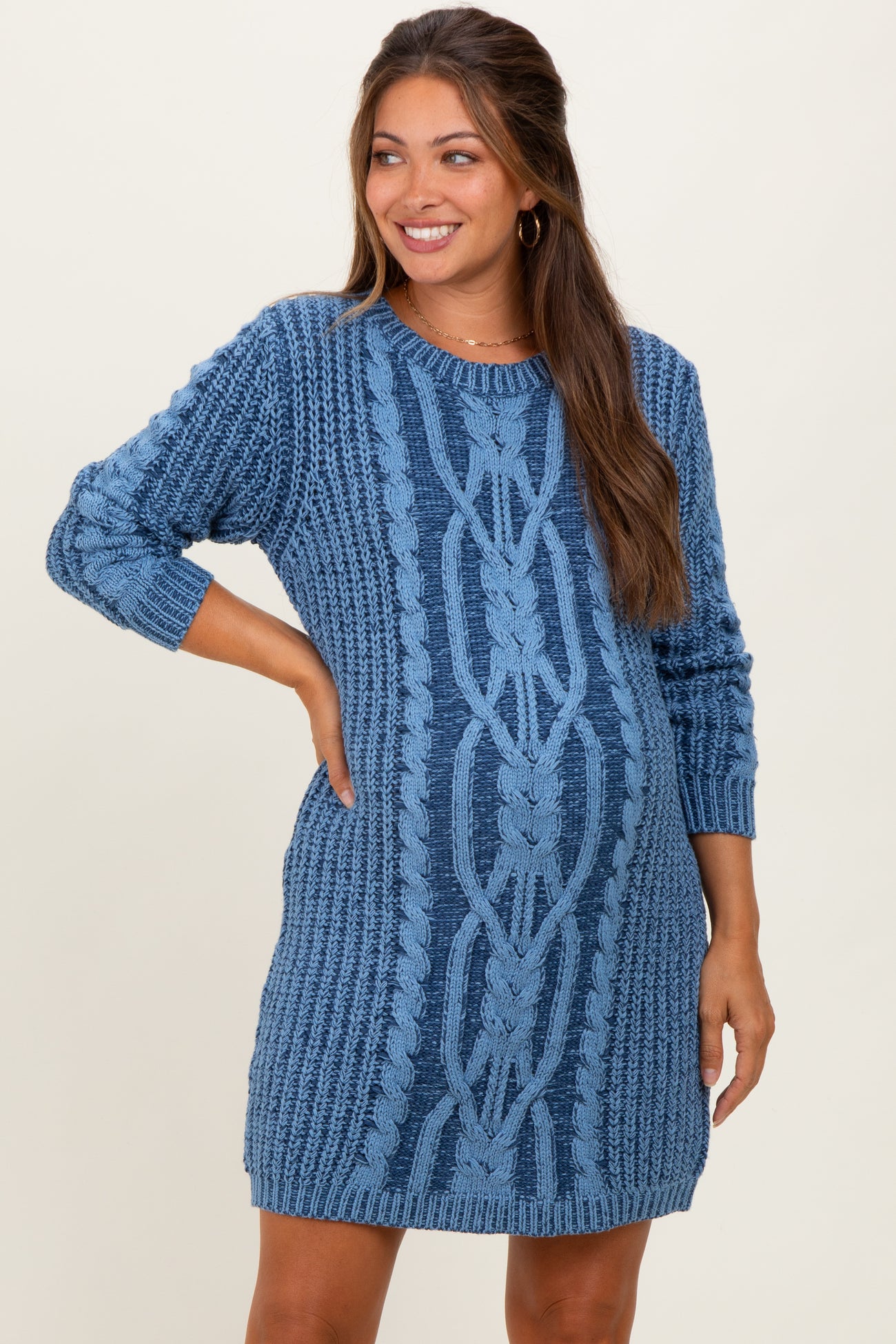 woman wearing a blue cable knit maternity sweater dress and showing her baby bump