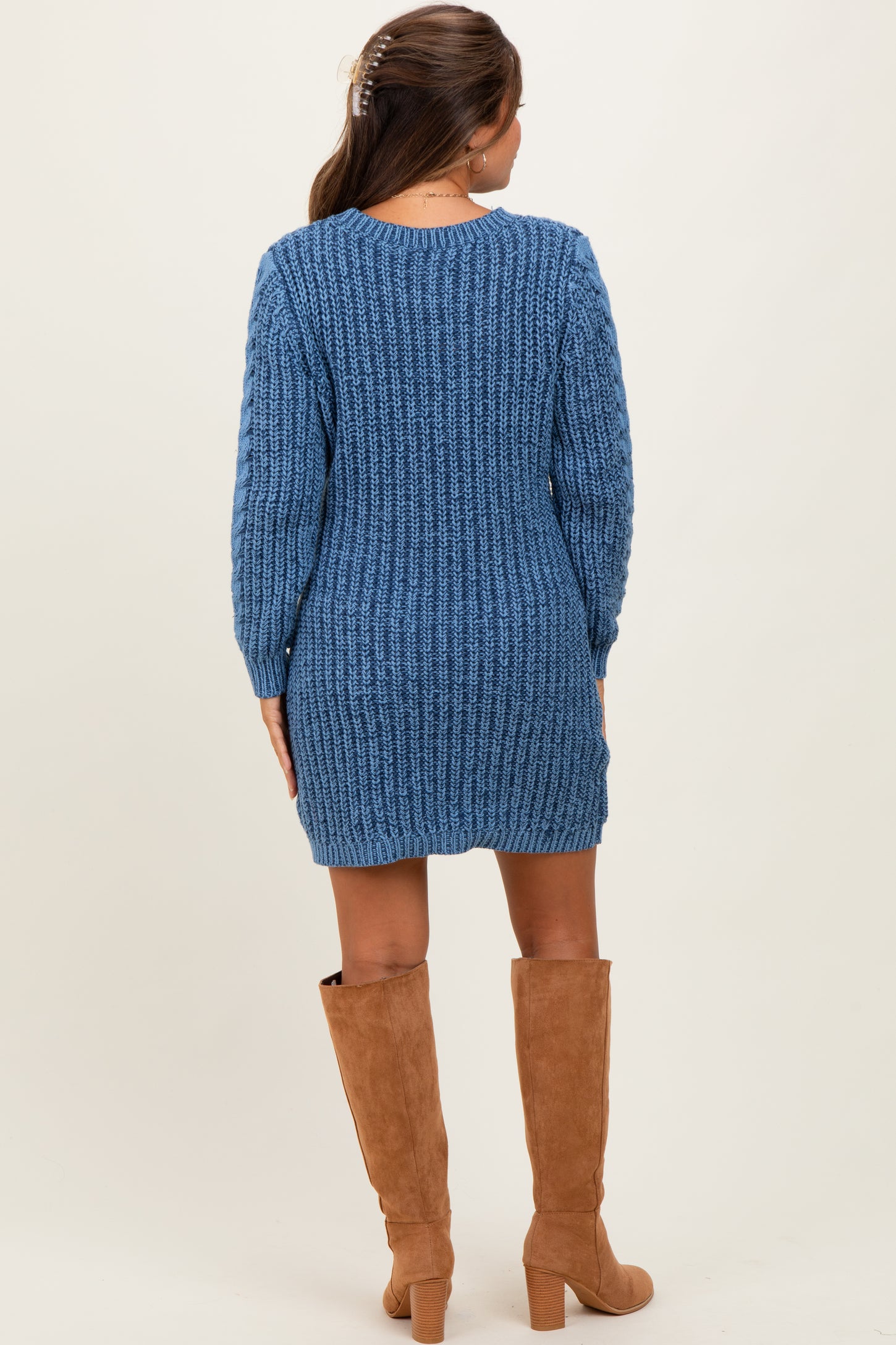 woman wearing a blue knitted maternity sweater dress with long sleeves and pairing it with knee-high tan boots