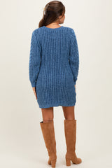 woman wearing a blue knitted maternity sweater dress with long sleeves and pairing it with knee-high tan boots