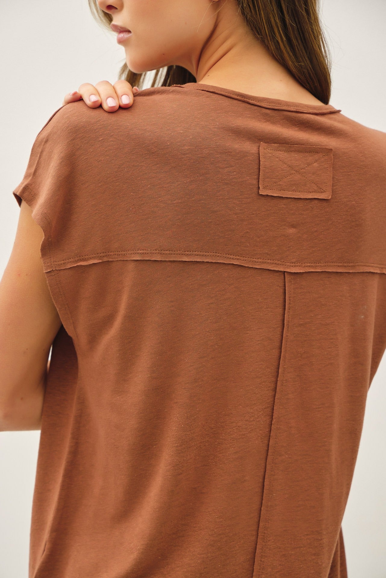 woman wearing a rust brown short sleeve top with a back yoke detail and patch pocket