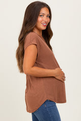 woman wearing a brown short sleeve maternity top and holding her baby bump