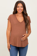 woman wearing a brown v-neck maternity top and holding her baby bump with a smile
