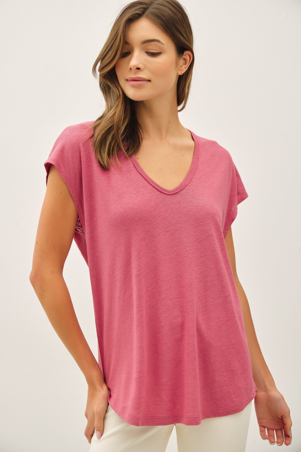 woman wearing a light pink short sleeve v-neck top with a relaxed fit and a slight hem detail