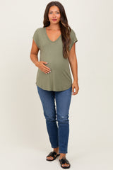 woman wearing an olive green maternity short sleeve top and holding her baby bump with blue jeans and sandals