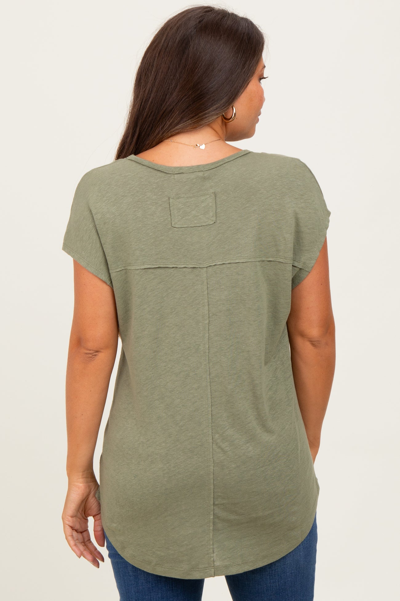 woman wearing a green short sleeve maternity top, showing the back and curved hem of the shirt