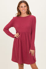 woman wearing a burgundy long sleeve ribbed dress with a flared skirt and round neckline