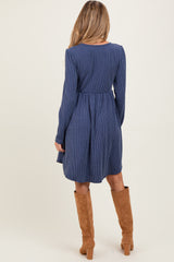 woman wearing a navy blue maternity dress with vertical stripes and long sleeves, paired with knee-high brown boots, showing her back