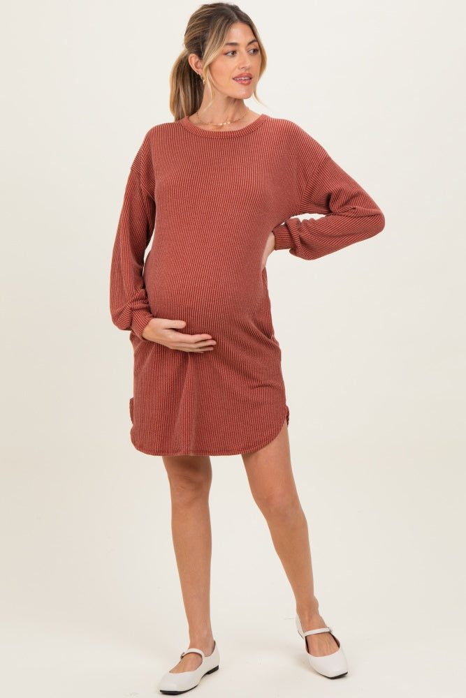 woman wearing a rust striped maternity dress with long sleeves and a visible baby bump