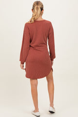woman wearing a rust-colored striped maternity dress with long sleeves and side slits, showing a baby bump