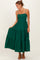 woman wearing a dark green tiered maxi dress with spaghetti straps and a fitted bodice, holding the skirt gently