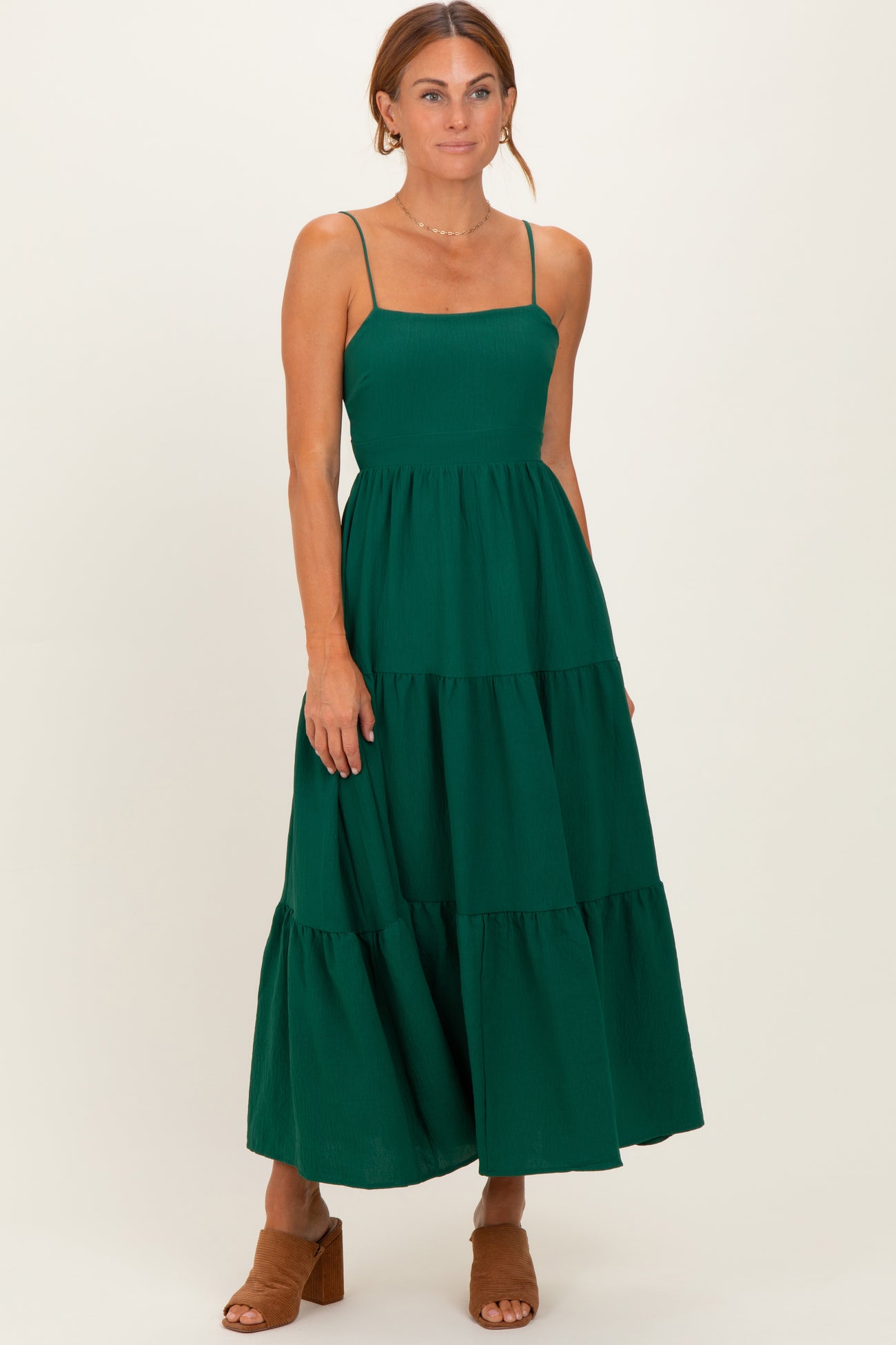 woman wearing a dark green tiered maxi dress with spaghetti straps and a fitted bodice