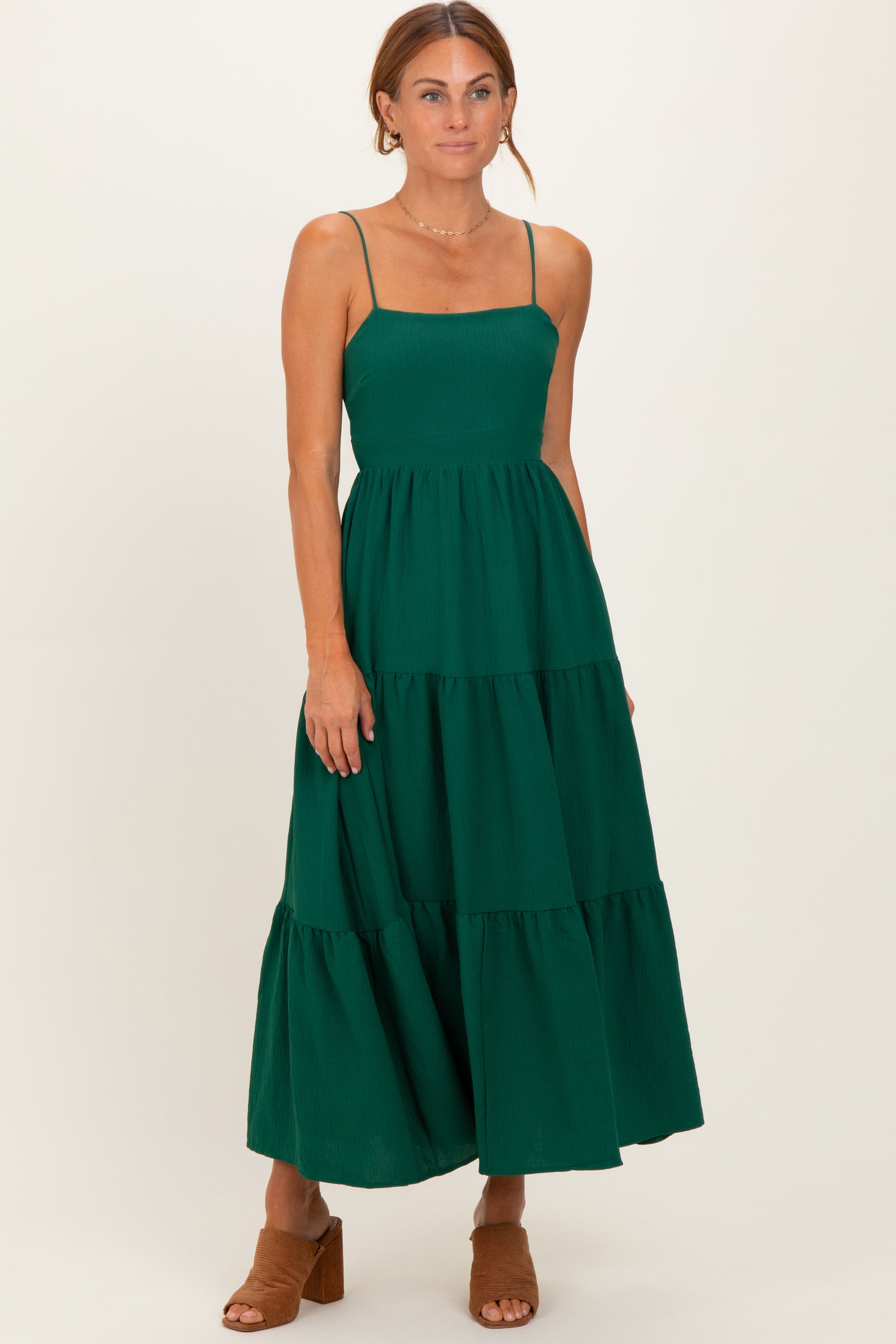 woman wearing a dark green tiered maxi dress with spaghetti straps and a fitted bodice