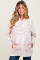 woman wearing a striped pink maternity hoodie with a button-up neckline and front pockets, showcasing her baby bump