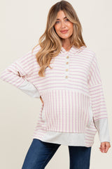 woman wearing a light pink and white striped maternity hoodie with buttons and a visible baby bump