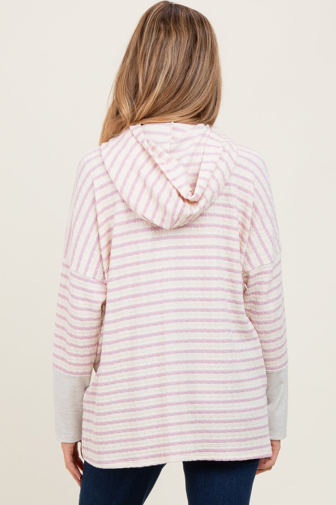 woman wearing a pink and white striped maternity hoodie with a hood and long sleeves, showing a relaxed fit from the back