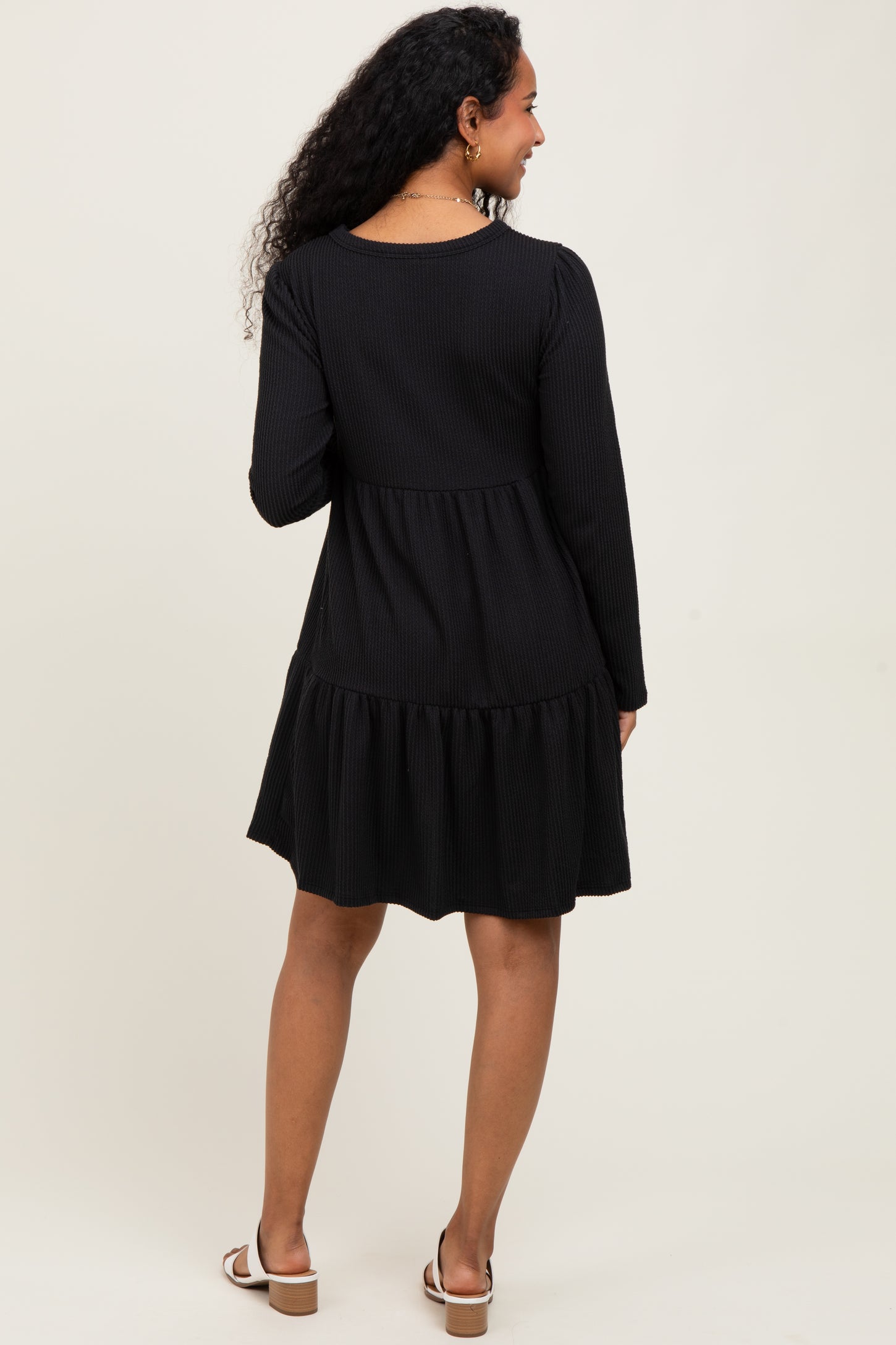woman wearing a black ribbed long sleeve maternity dress with a tiered skirt and back view shown