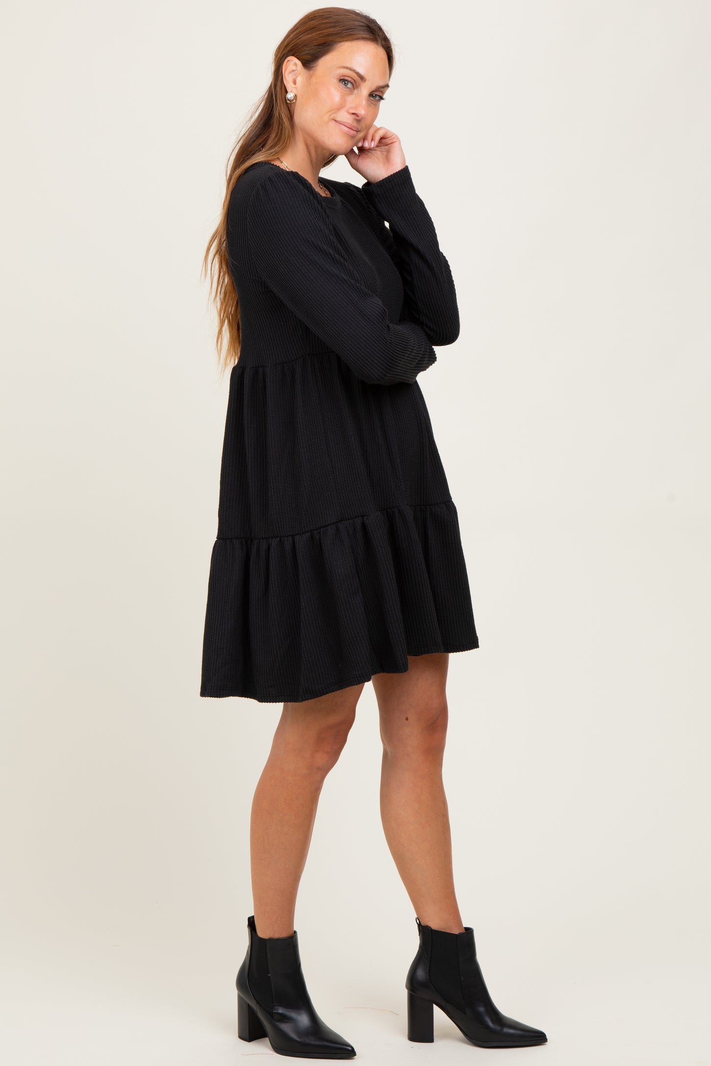 woman wearing a black tiered long sleeve dress with a relaxed fit and ankle boots