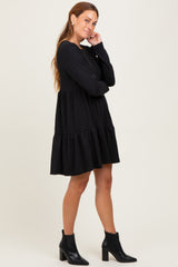 woman wearing a black tiered long sleeve dress with a relaxed fit and ankle boots