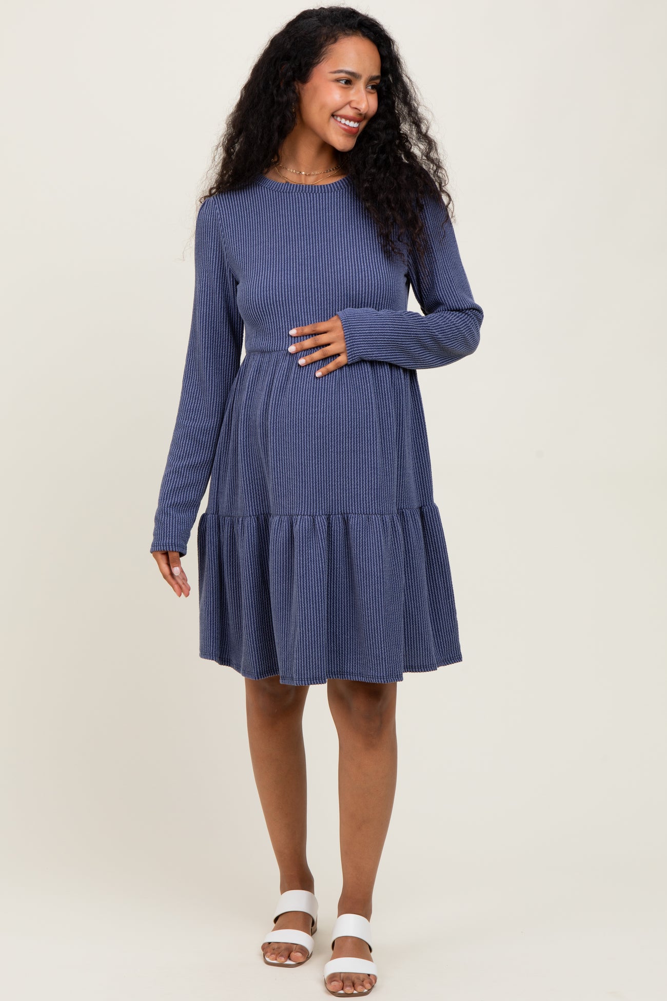 woman wearing a navy blue striped long sleeve maternity dress with a tiered skirt and visible baby bump
