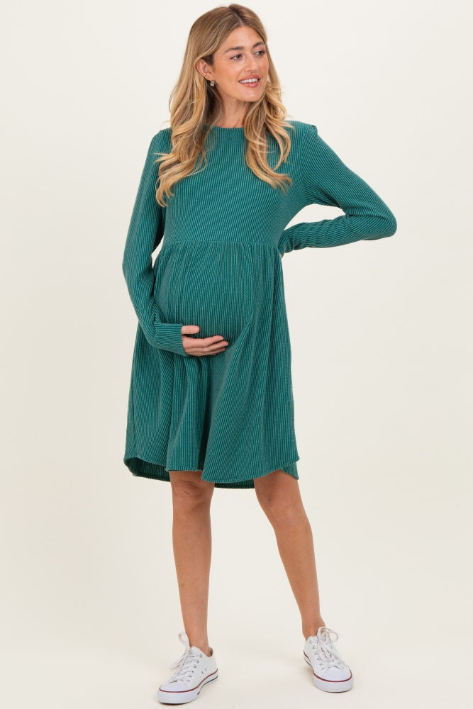 woman wearing a teal long sleeve maternity dress holding her baby bump