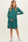 woman wearing a teal long sleeve maternity dress holding her baby bump