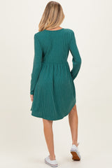 woman wearing a green ribbed long sleeve maternity dress with a flared skirt, showing a baby bump from behind