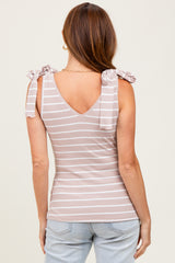 woman wearing a soft pink and white striped sleeveless top with bow tie details on the shoulders