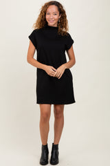 woman wearing a black short sleeve casual dress with a high neckline and standing confidently