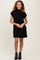 woman wearing a black short sleeve casual dress with a high neckline and standing confidently