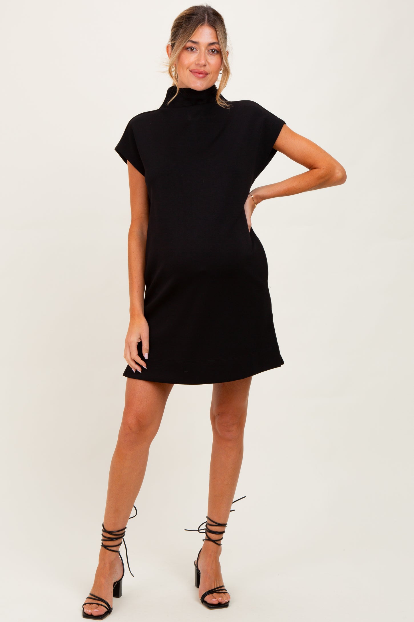 woman wearing a black maternity dress with a mock neck and relaxed fit, showcasing her baby bump