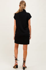 woman wearing a black short sleeve maternity dress with a high neckline, viewed from the back